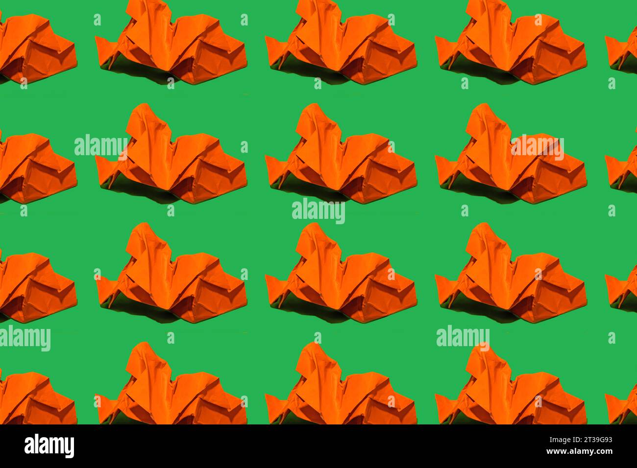 Motif répétitif de figures de papier froissé orange régulièrement espacées sur un fond vert vif. Banque D'Images