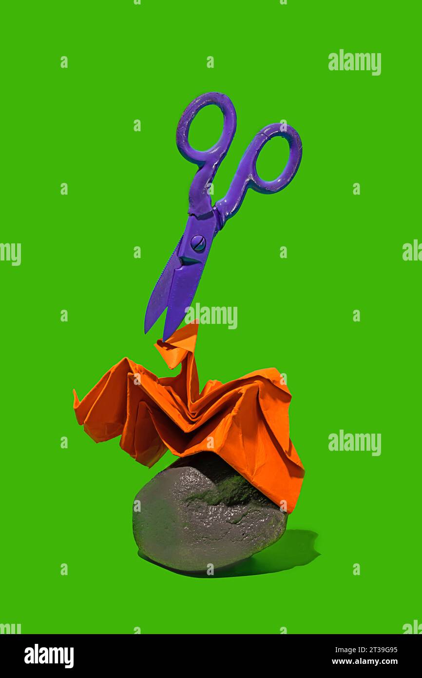 Une image vibrante montrant un ciseaux violets planant au-dessus d'une figure de papier orange finement pliée qui repose sur un rocher, le tout contre un g lumineux Banque D'Images