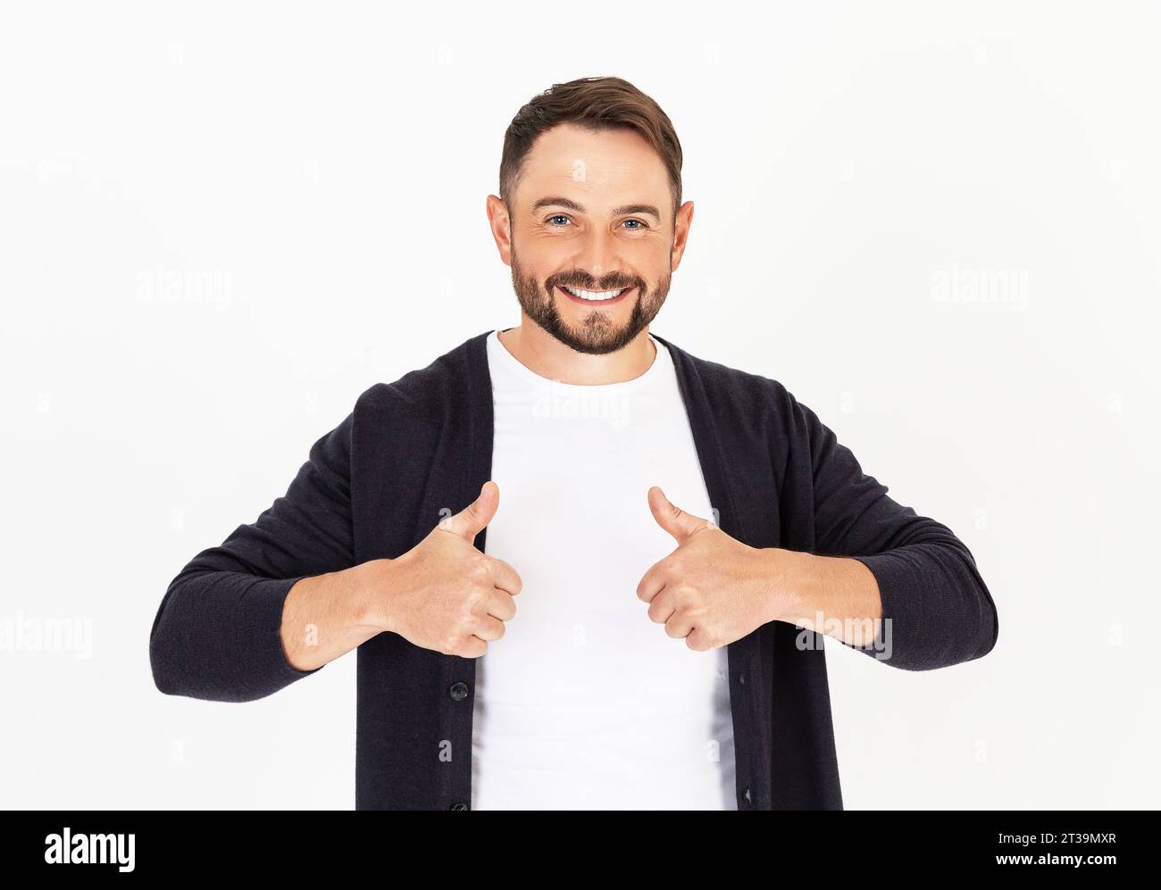 Jeune bel homme avec barbe portant des vêtements décontractés sur un fond blanc, approuvant faire un geste positif avec la main, les pouces vers le haut. Homme souriant et hap Banque D'Images