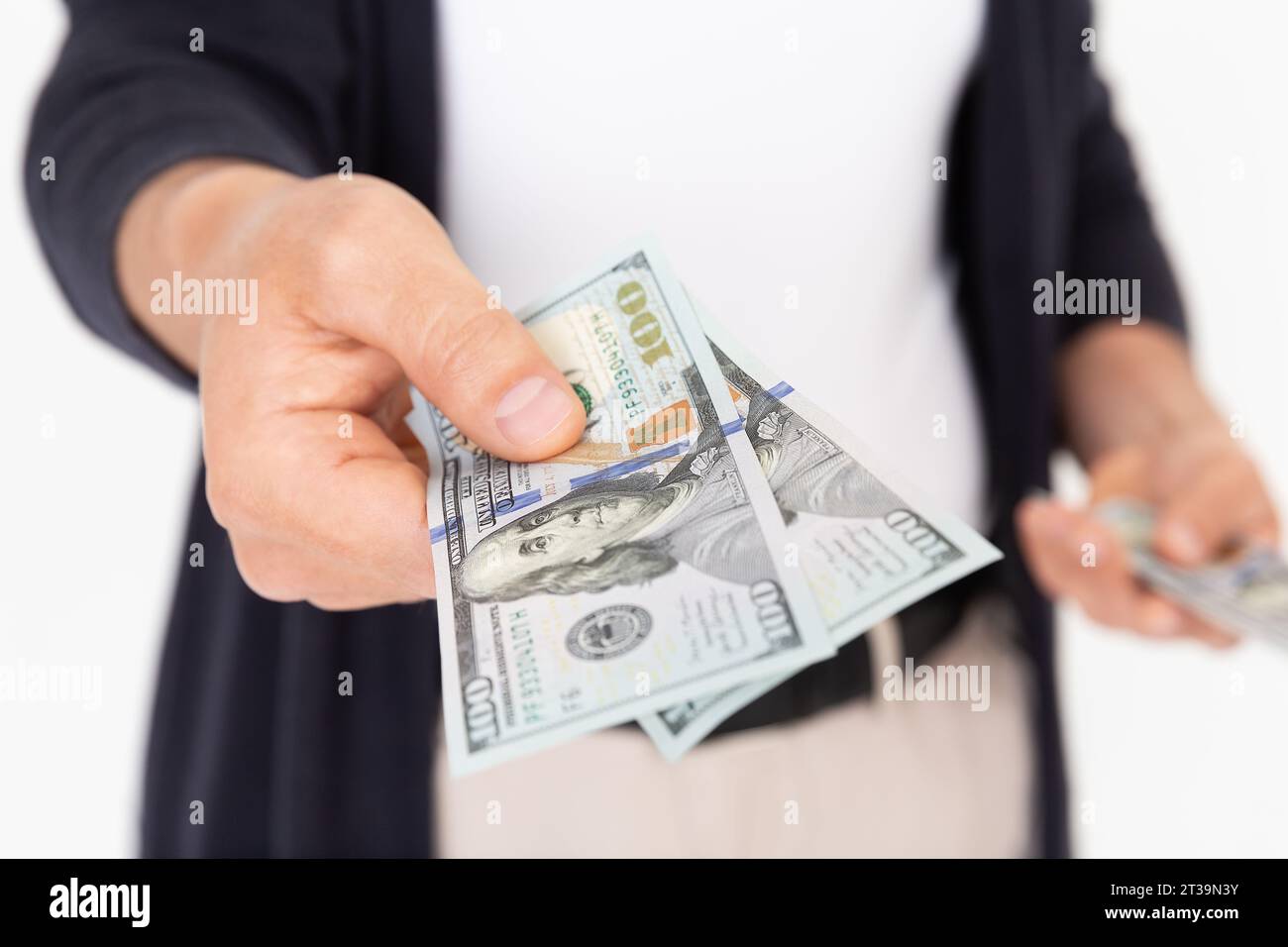 Jeune homme prospère tenant deux billets de 100 dollars sur un fond blanc. Un homme prête 200 dollars. Banque D'Images
