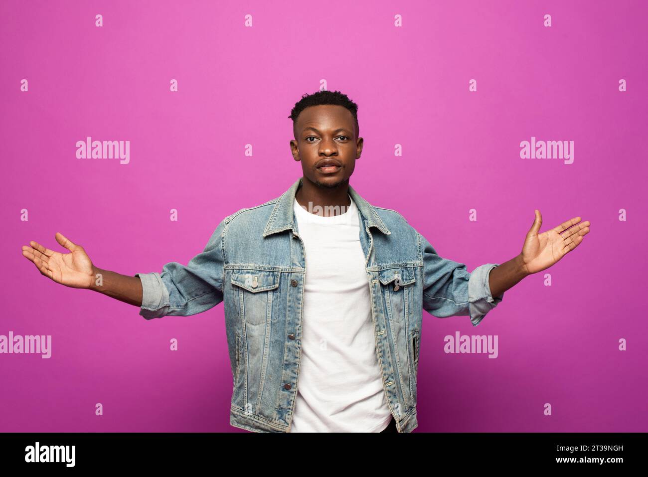 Jeune homme africain regardant la caméra avec le geste de main ouverte en fond isolé de studio de couleur violette Banque D'Images