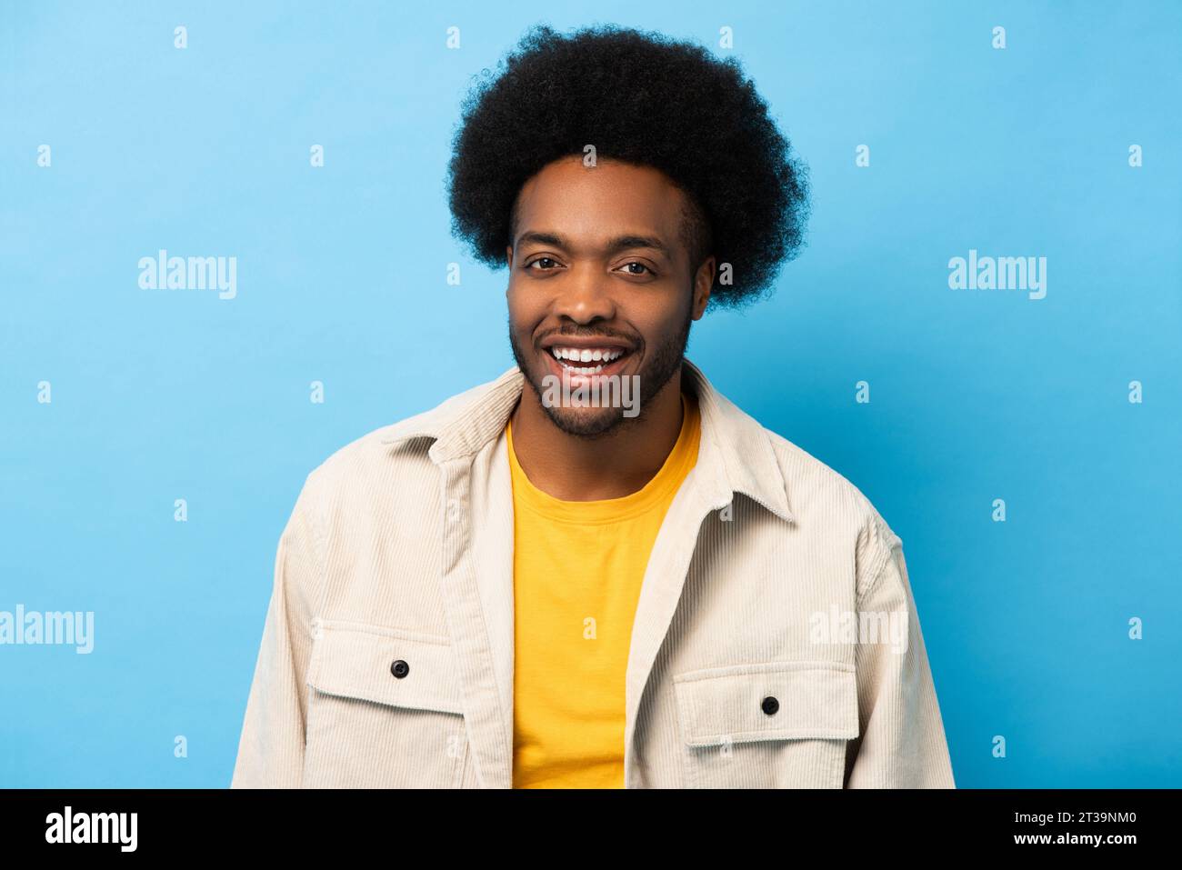 Heureux positif afro-américain homme souriant et regardant la caméra en fond bleu clair isolé studio tourné Banque D'Images