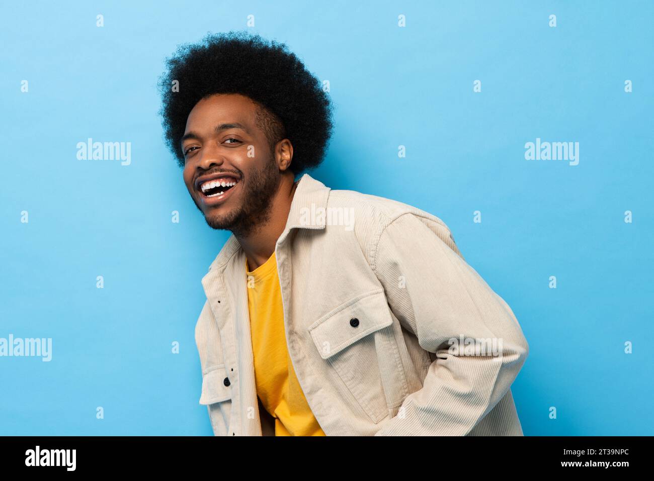 Heureux positif afro-américain homme riant et regardant la caméra en bleu clair isolé fond studio tourné Banque D'Images