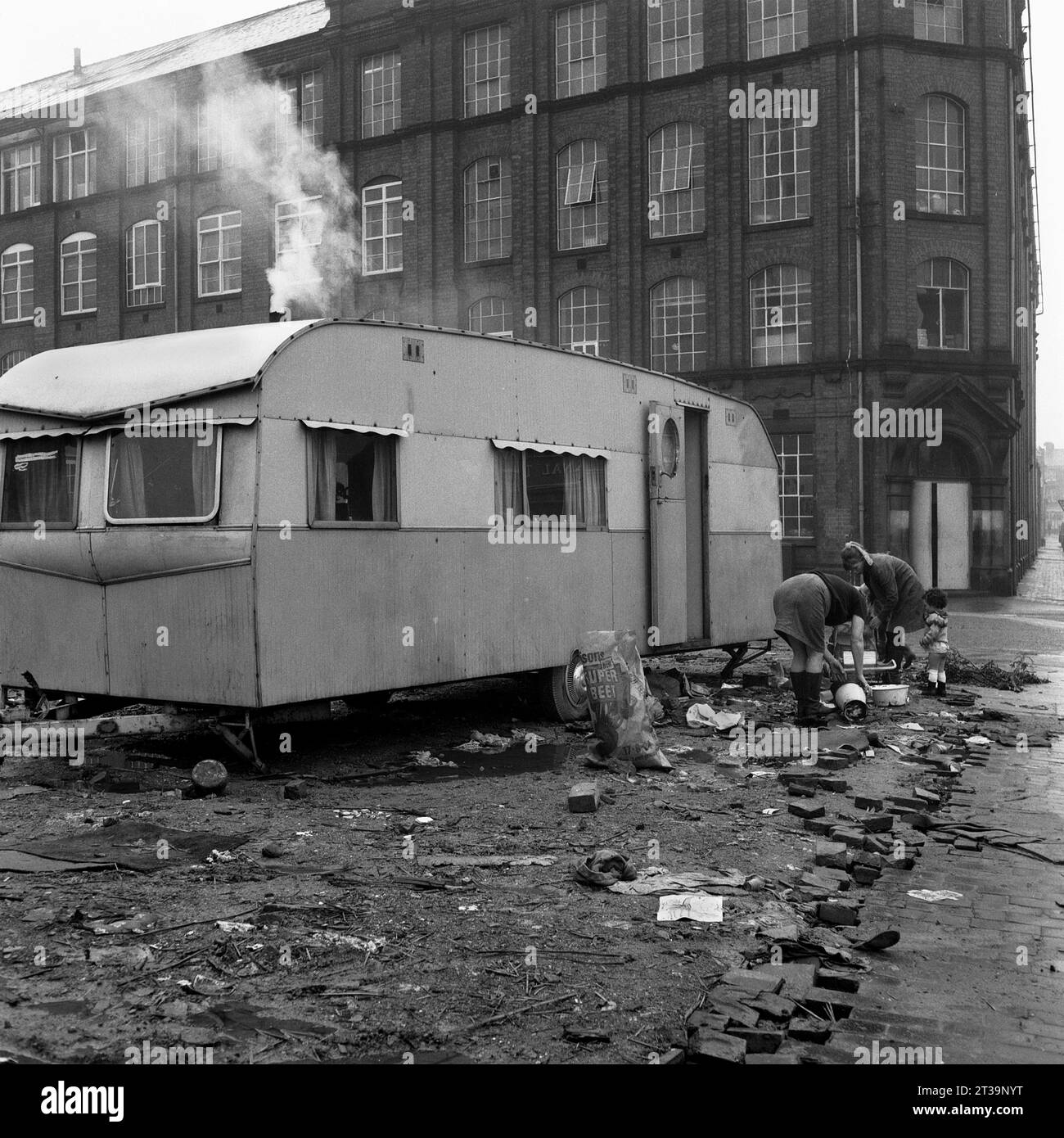 La famille des voyageurs et leur caravane garés sur des terres vagues à côté d'une usine pendant le déminage et la démolition de St ann's, Nottingham. 1969-1972 Banque D'Images