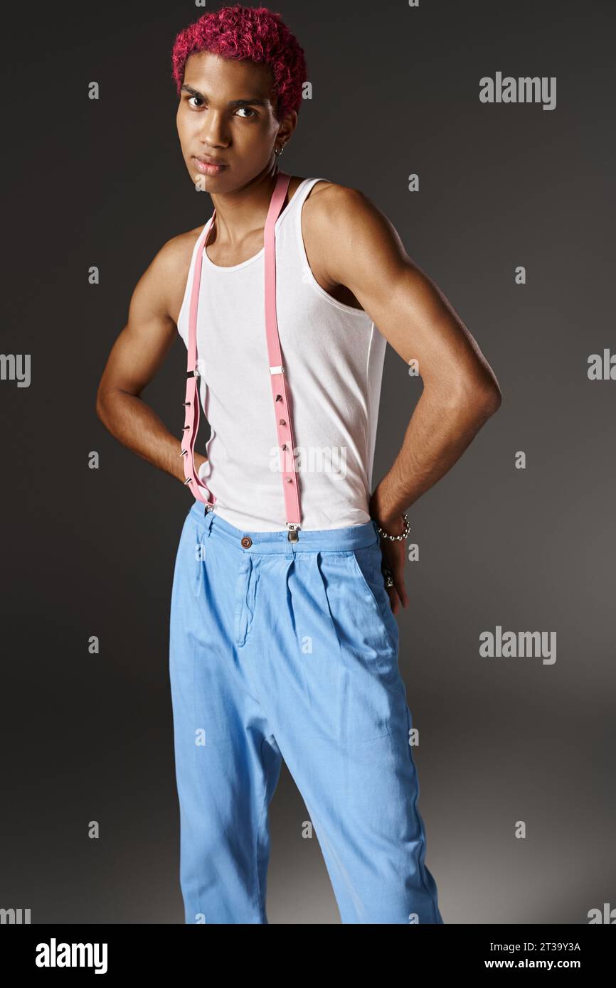 bon modèle masculin posant avec les mains derrière le dos dans un pantalon bleu sur fond gris, mode Banque D'Images