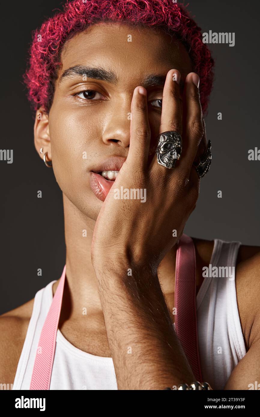 portrait de jeune modèle masculin élégant portant des accessoires argentés avec la main sur le visage, concept de mode Banque D'Images