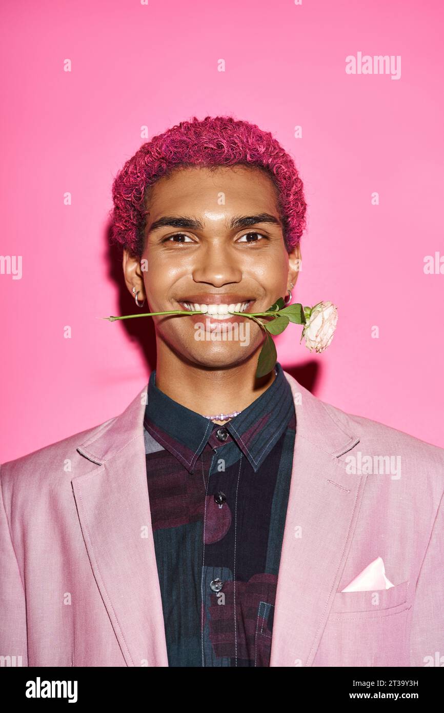 portrait de jeune homme joyeux avec rose blanche dans la bouche souriant à la caméra et agissant comme poupée Banque D'Images