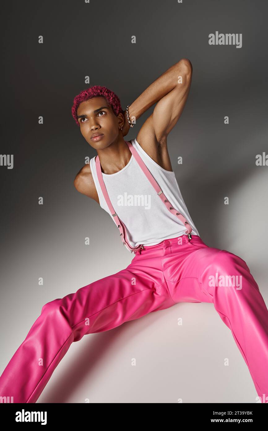 bon modèle masculin à la recherche avec les cheveux roses assis sur le sol avec la main derrière le cou, concept de mode Banque D'Images