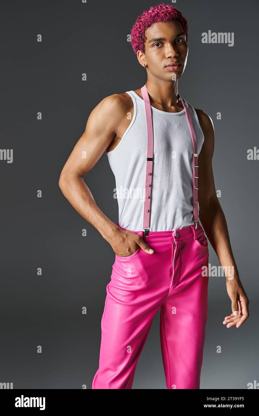 jeune modèle masculin aux cheveux roses posant sur fond gris avec une main dans la poche, la mode et le style Banque D'Images