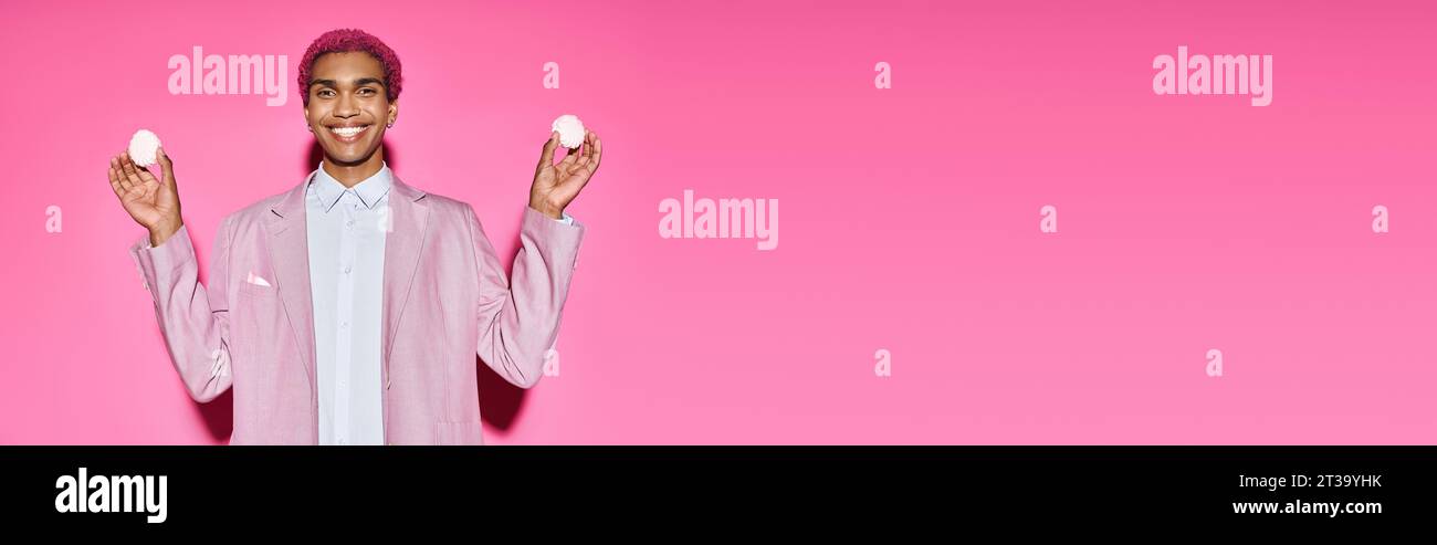 bon modèle masculin souriant anormalement et tenant un délicieux zéfir dans ses mains, bannière Banque D'Images