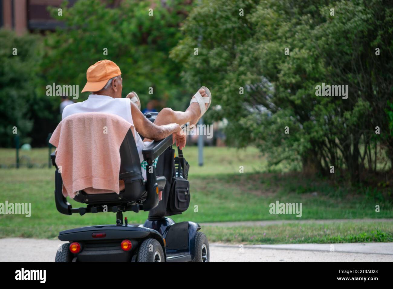 Homme âgé couché avec les jambes vers le haut dans un fauteuil roulant électrique montrant divers concepts Banque D'Images