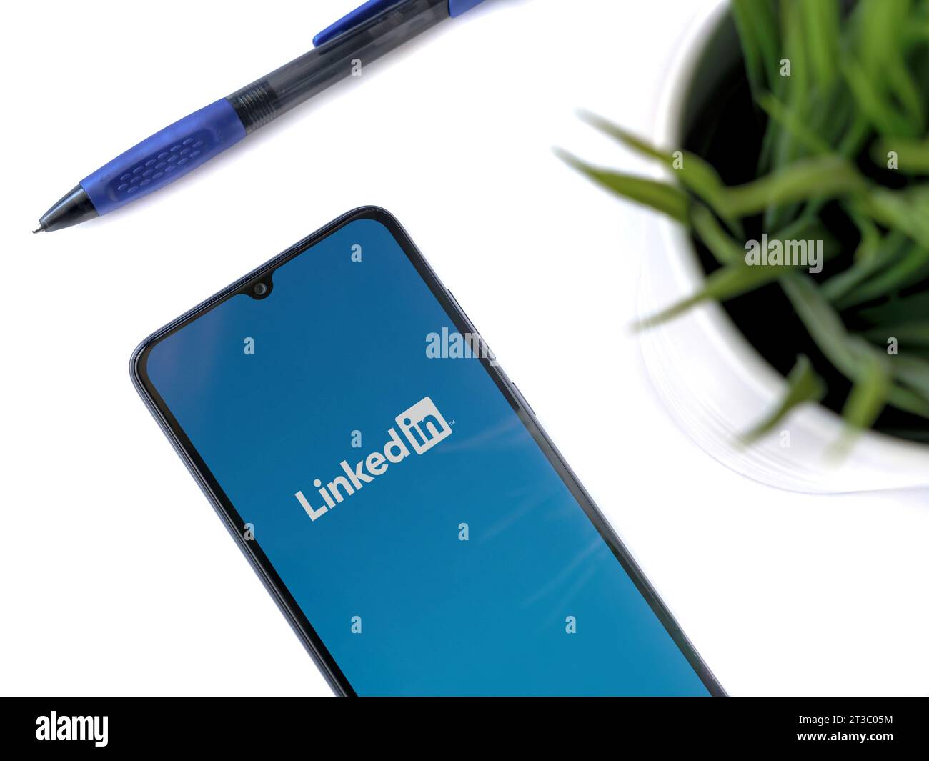 LOD, Israël - 16 juillet 2023 : espace de travail moderne avec smartphone avec écran de lancement de l'application LinkedIn sur fond blanc. Gros plan vue de dessus à plat. Banque D'Images