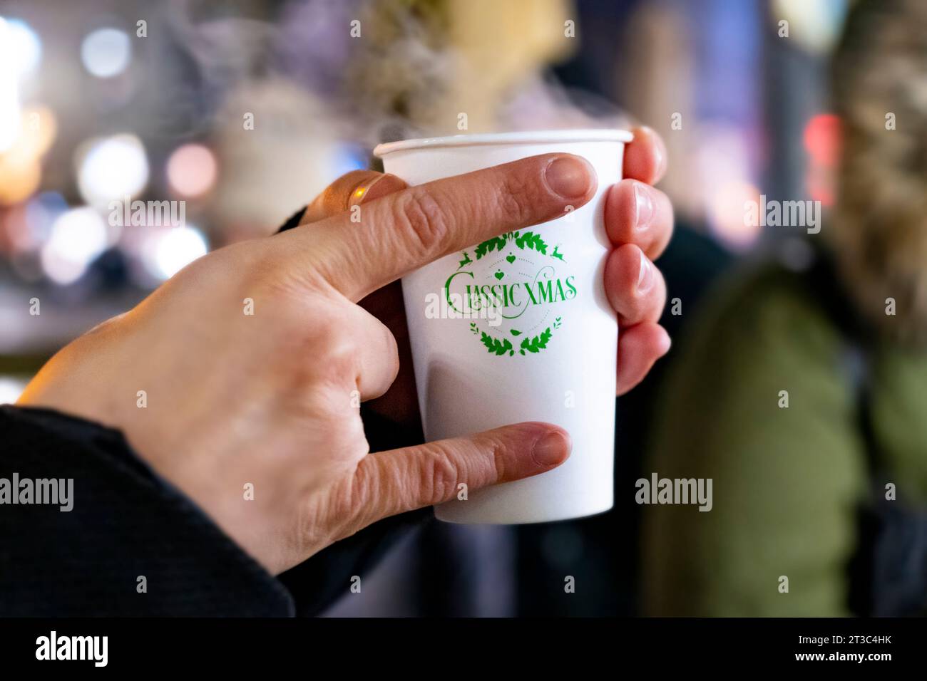 Une main tenant une boisson chaude dans une tasse de Noël en plastique sur un marché de Noël Banque D'Images