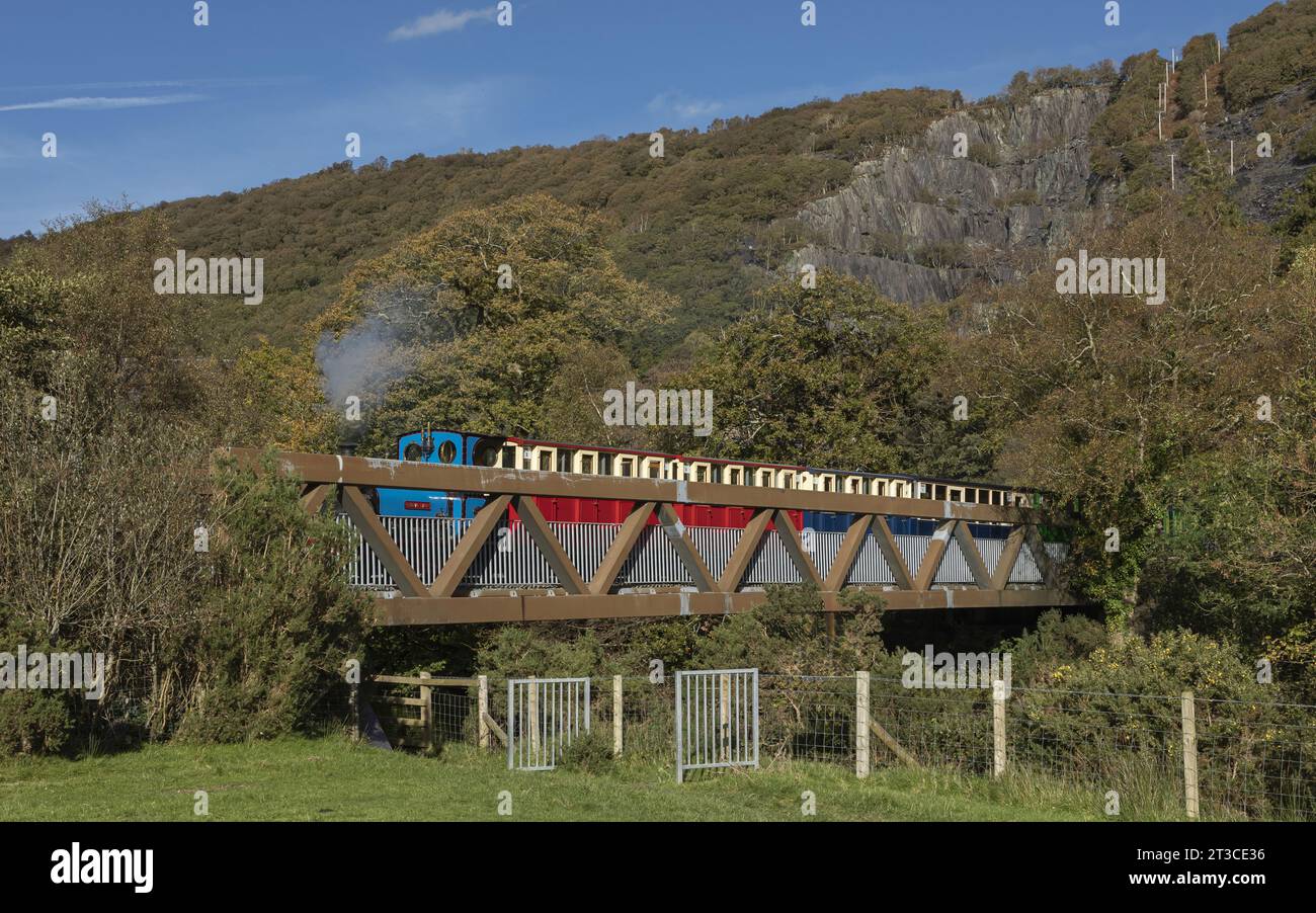 Train à vapeur touristique traversant un pont métallique sur fond de montagne Banque D'Images