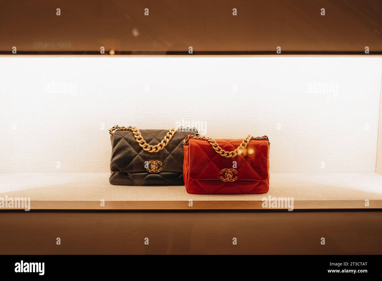 Sacs à main Chanel féminins orange chic rouge et noir avec chaîne dorée dans la fenêtre d'un magasin de luxe. Chanel est une marque de haute couture fondée par Coco C. Banque D'Images