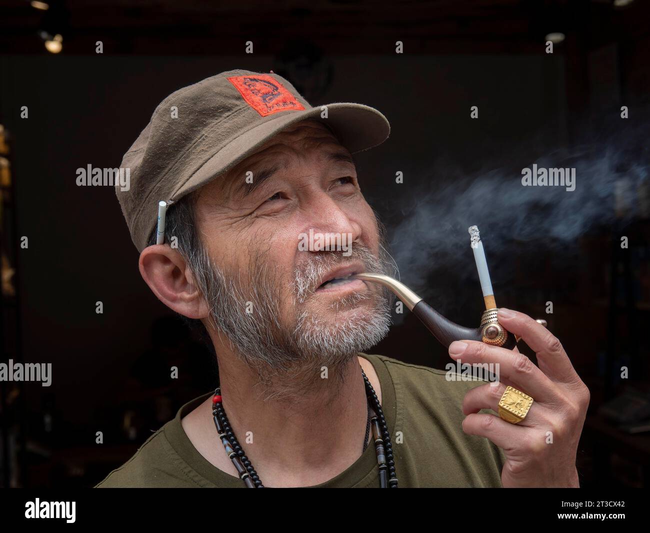 Homme avec barbe, casquette de baseball et pipe à tabac, Xizhou, Yunnan, Chine Banque D'Images