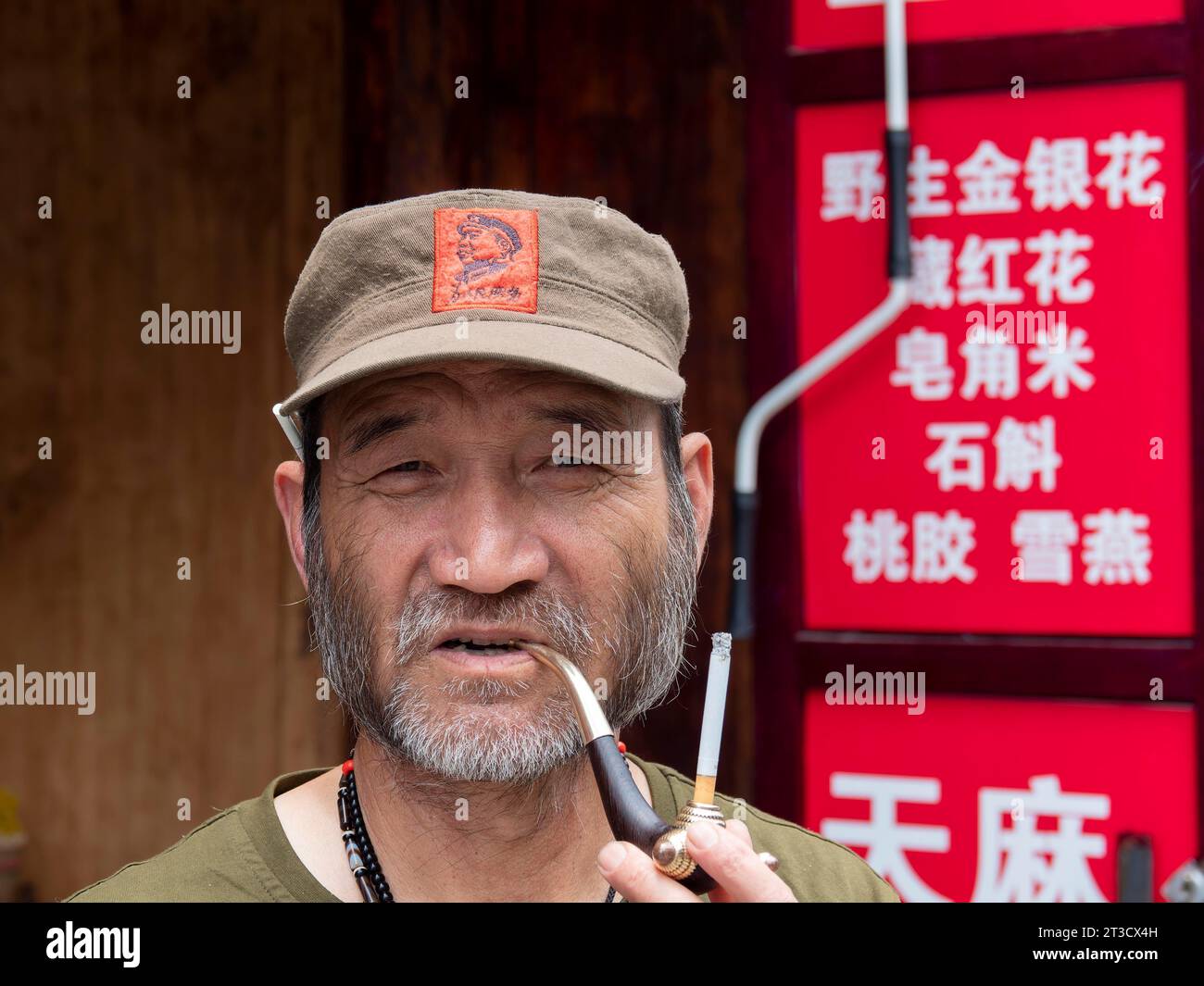 Homme avec barbe, casquette de baseball et pipe à tabac, Xizhou, Yunnan, Chine Banque D'Images