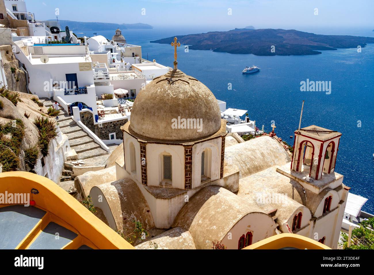 Surplombant la caldeira et la mer Égée depuis l'île grecque de Santorin baignée de soleil depuis la ville de Fira, une église en dôme au premier plan. Banque D'Images