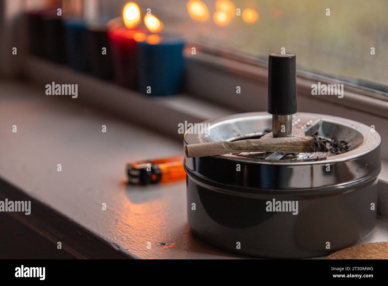 Un joint (cigarette de cannabis roulée) et cendrier placés près de la fenêtre de la pièce. La marijuana comme article de luxe, les questions sociales et la légalisation du cannabis Banque D'Images