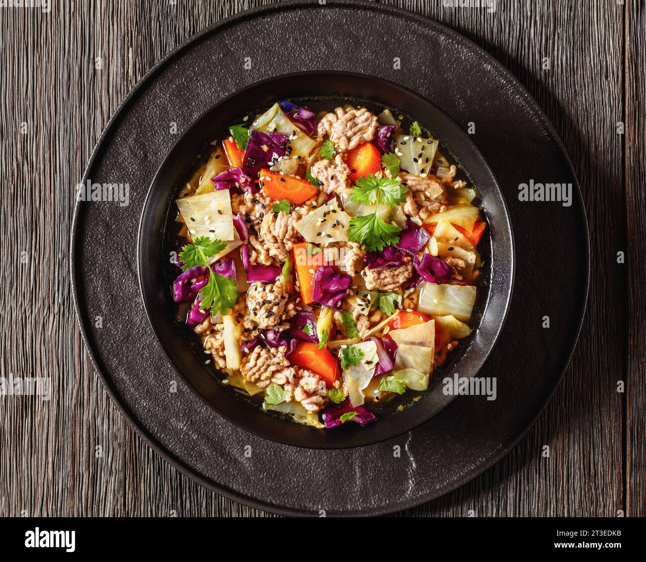 soupe au chou roulé aux œufs avec du porc haché et des légumes dans un bol noir sur une table en bois sombre avec cuillère, cuisine asiatique, vue horizontale d'en haut, plat l Banque D'Images