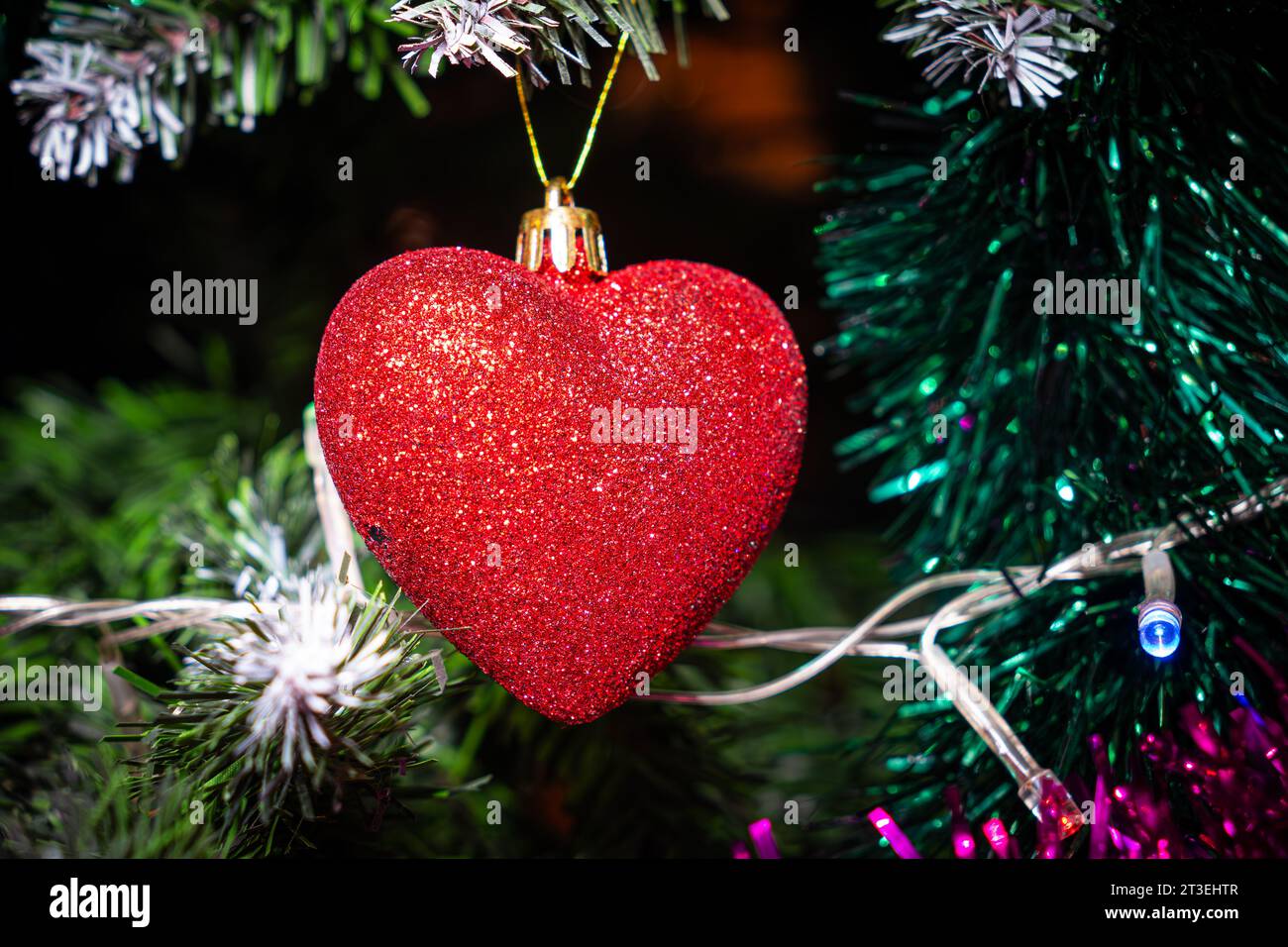 Ornements rouges de noël, coeur sur l'arbre de Noël sur fond de bokeh scintillant avec des lumières scintillantes. Carte de joyeux noël. Thème des vacances d'hiver. Joyeux Nouveau Banque D'Images