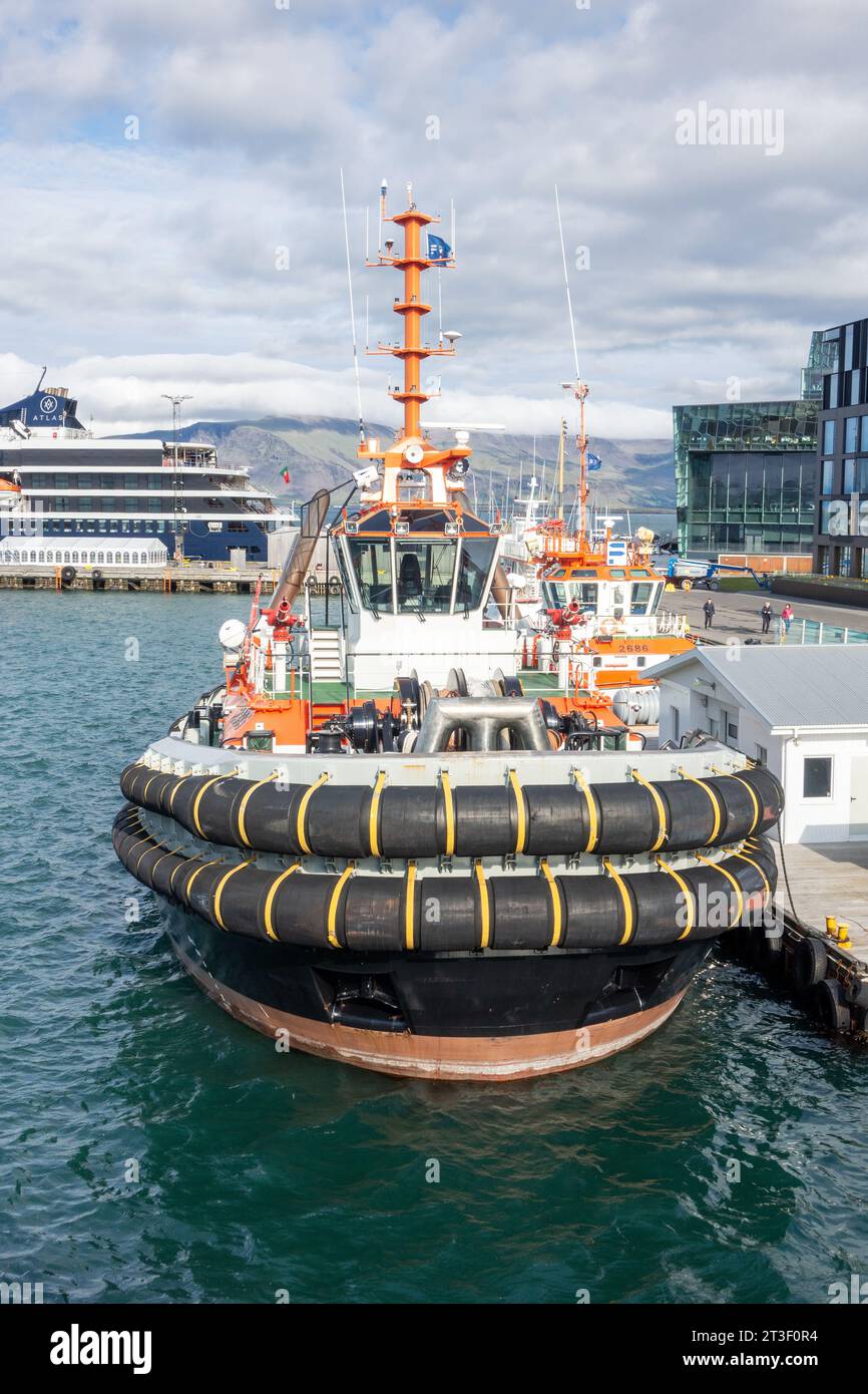 Atlas Ocean Voyages World Traveller petit bateau de croisière de style yacht à Port Reykjavik Islande avec des Tugboats à l'extérieur du Harpa Centre Banque D'Images