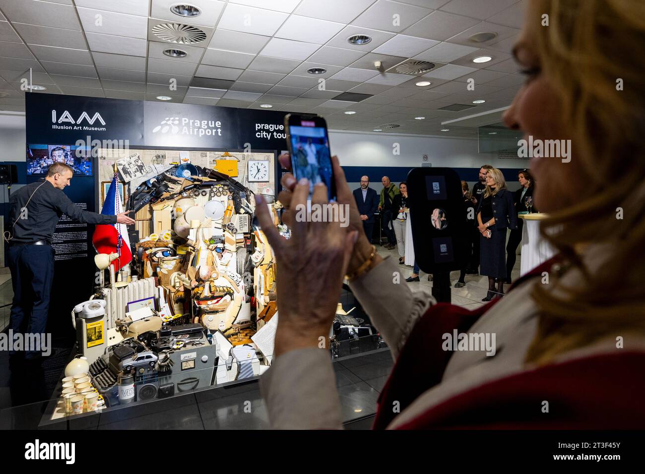 Prague, République tchèque. 25 octobre 2023. Dévoilement cérémoniel d’un portrait en 3D composé de milliers d’objets racontant l’histoire de la vie de Vaclav Havel, réalisé par le sculpteur Patrik Prosko, Vaclav Havel Airport Prague, terminal 2 à l’installation Forum Havlum, le 25 octobre 2023. La veuve de Havel, Dagmar, est photographiée ici en train de photographier l'œuvre. Crédit : Ondrej Deml/CTK photo/Alamy Live News Banque D'Images