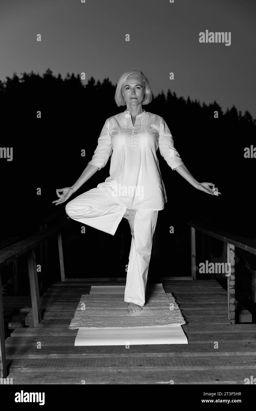 femme d'âge moyen faisant du yoga à l'extérieur dans la forêt Banque D'Images