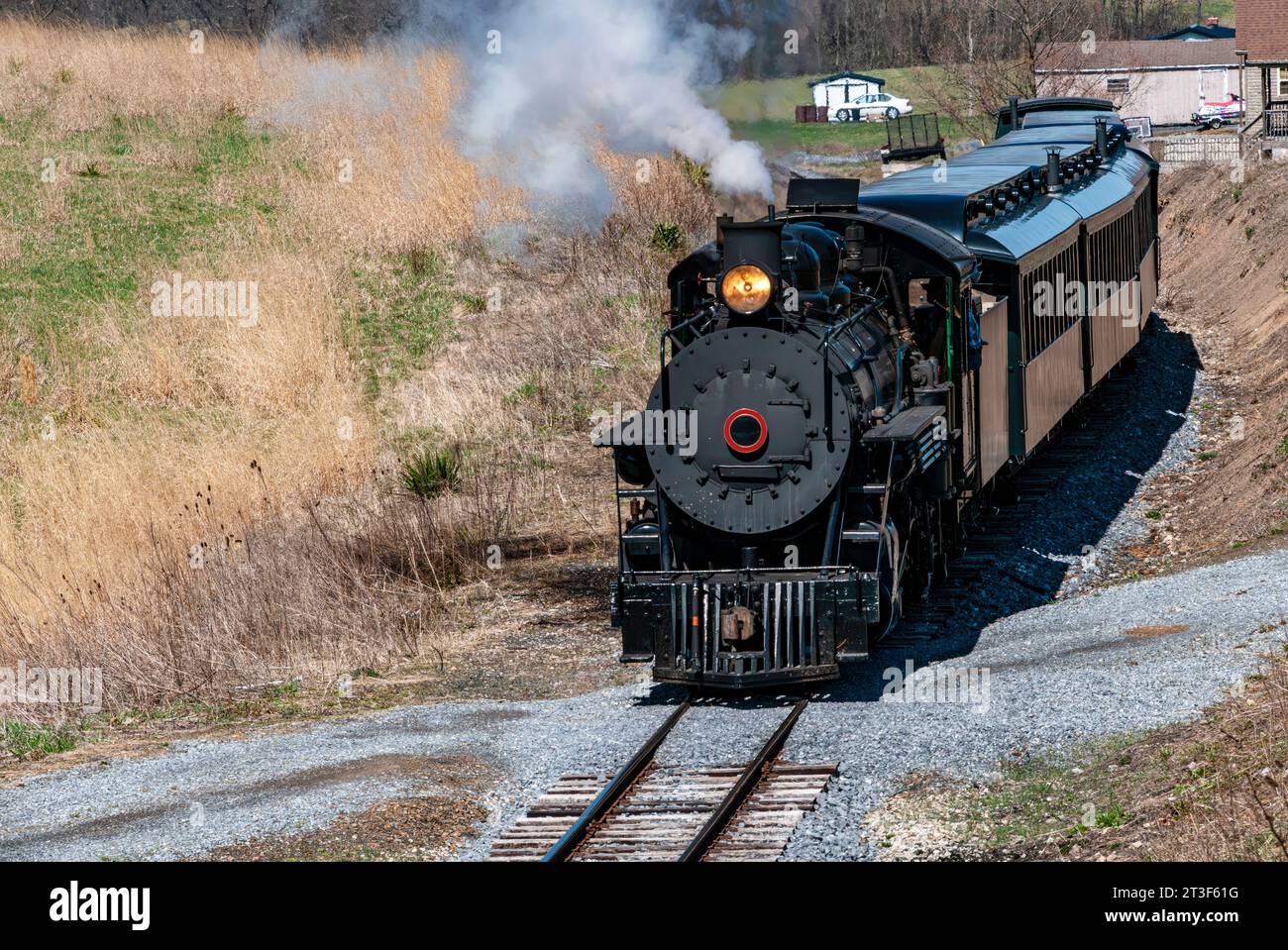 Vue avant et légèrement au-dessus d'un train de vapeur de passager à voie étroite à l'approche restauré, fumée et vapeur soufflantes lors d'une Sunny hiver Banque D'Images