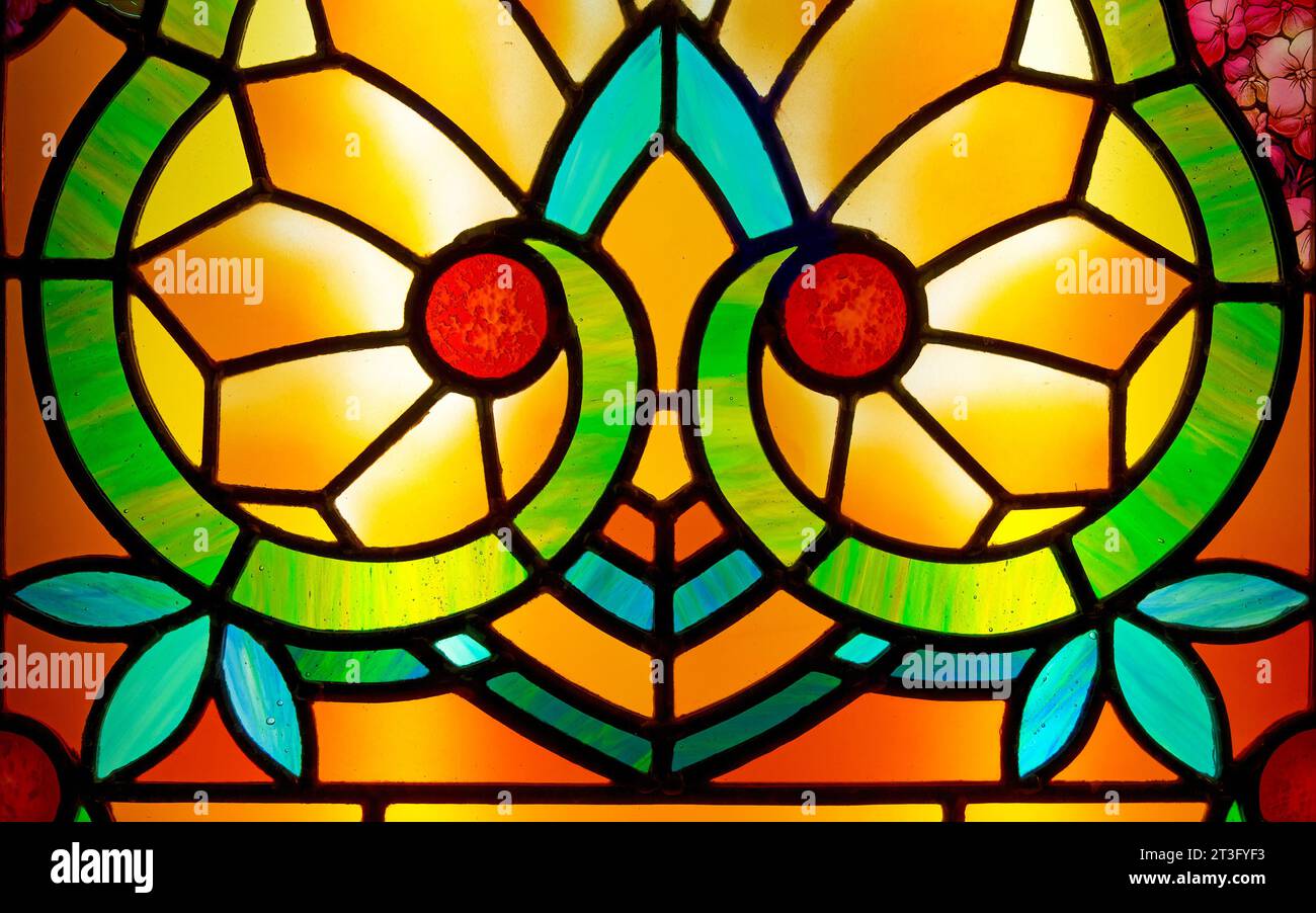 Petit détail d'un vitrail de style Art Nouveau générique. Tons jaune orange et rouge, avec des notes florales bleues et vertes. Banque D'Images