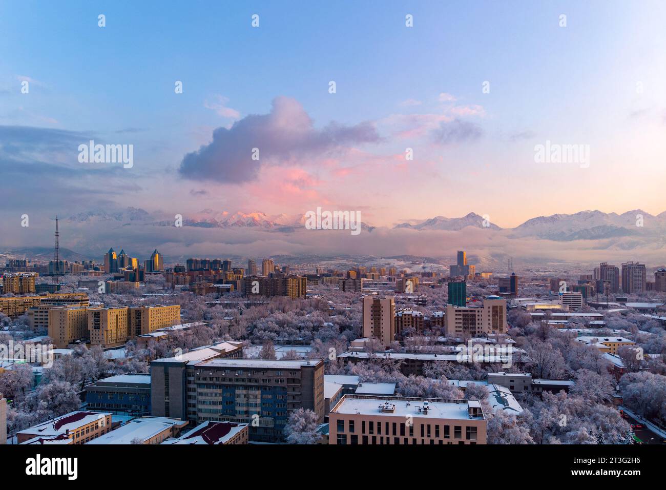 Vue sur la ville d'Almaty en soirée après de fortes chutes de neige. Les arbres sont couverts de neige, le soleil illumine magnifiquement les montagnes avec le coucher du soleil pi Banque D'Images