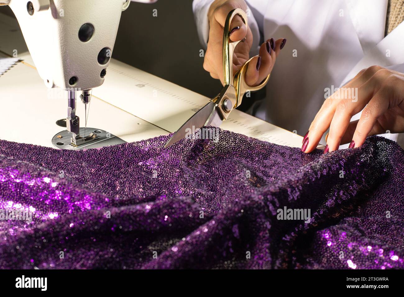 Taillez les mains au travail sur la machine à coudre et les ciseaux gros plan créateur de mode sur le lieu de travail Banque D'Images