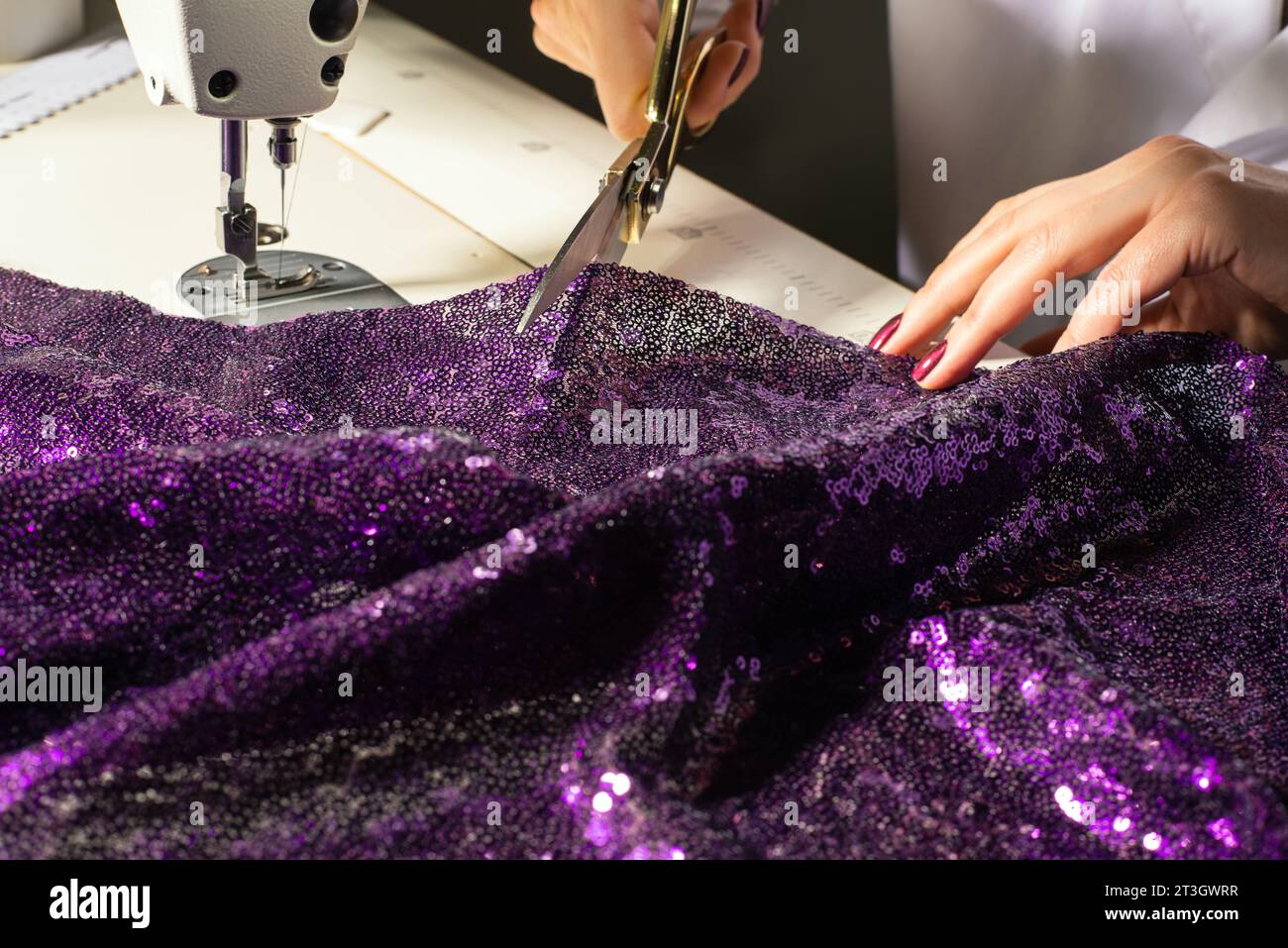 Taillez les mains au travail sur la machine à coudre et les ciseaux gros plan créateur de mode sur le lieu de travail Banque D'Images