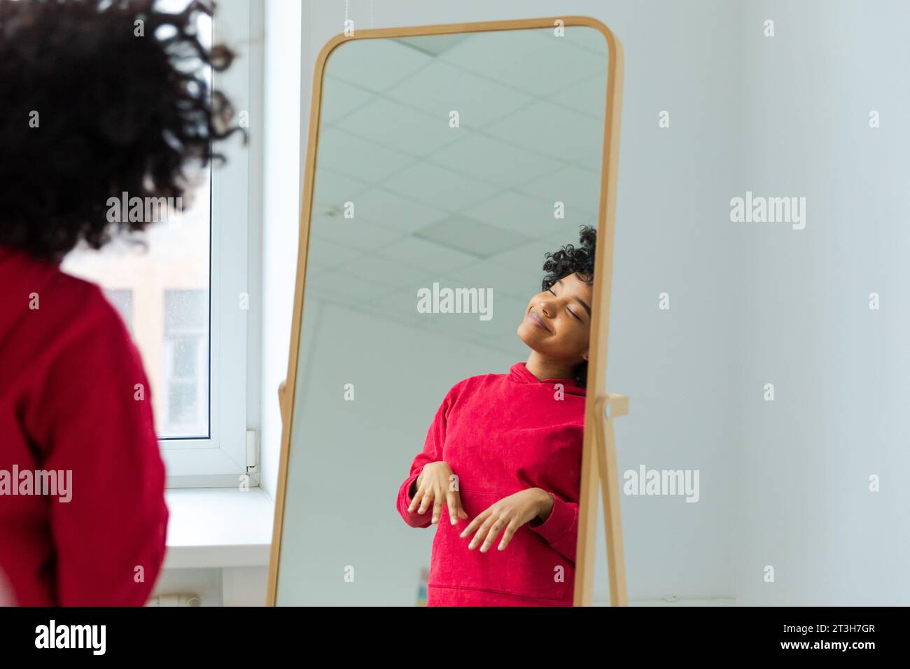 Aimez-vous. Belle jeune femme afro-américaine souriante dansant en appréciant sa réflexion miroir. Femme noire regardant le miroir regardant confiant et heureux. Concept d'amour de soi Banque D'Images