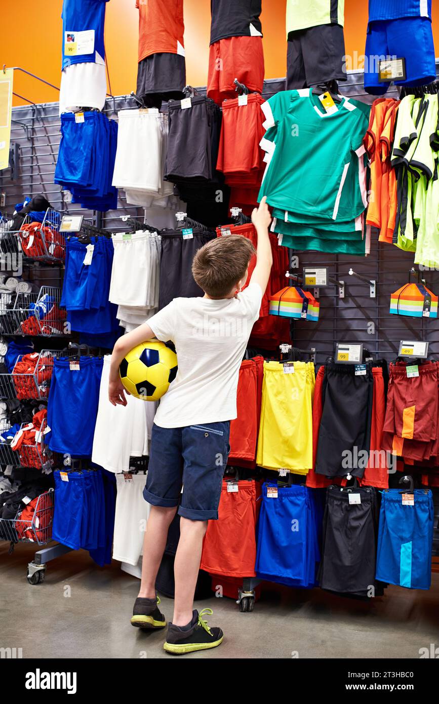 Garçon avec un ballon dans un magasin de vêtements de football Banque D'Images