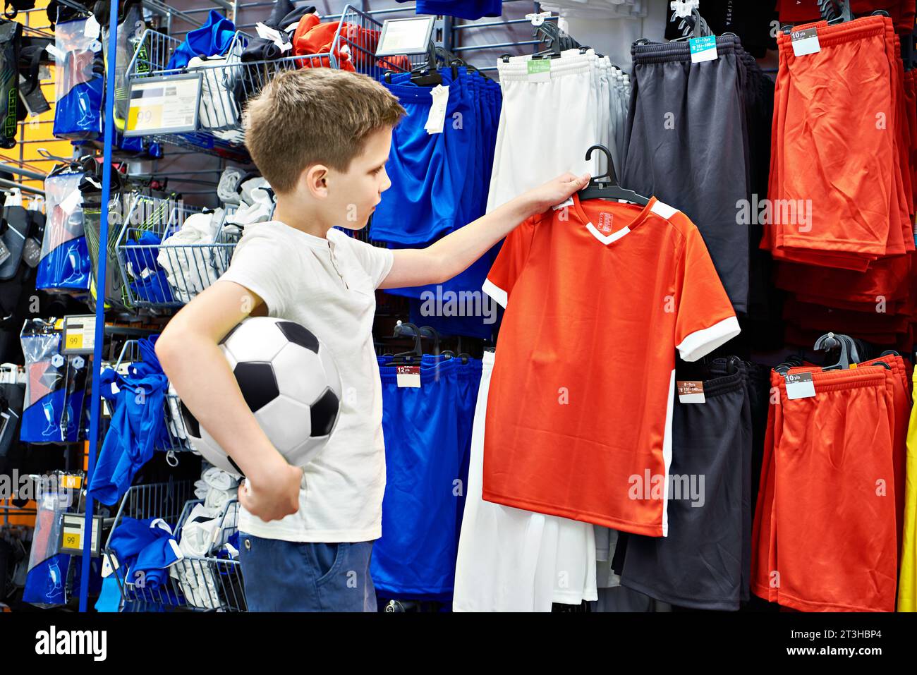 Garçon avec ballon de football dans un magasin de vêtements de football Banque D'Images