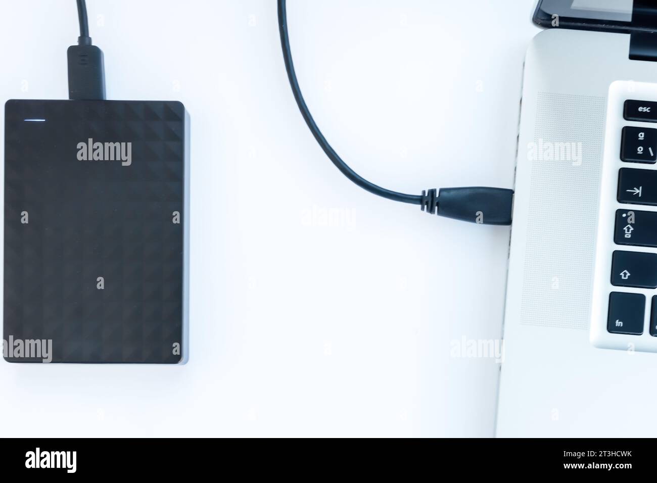 disque dur ssd noir avec câble connecté à un ordinateur portable avec fond blanc Banque D'Images