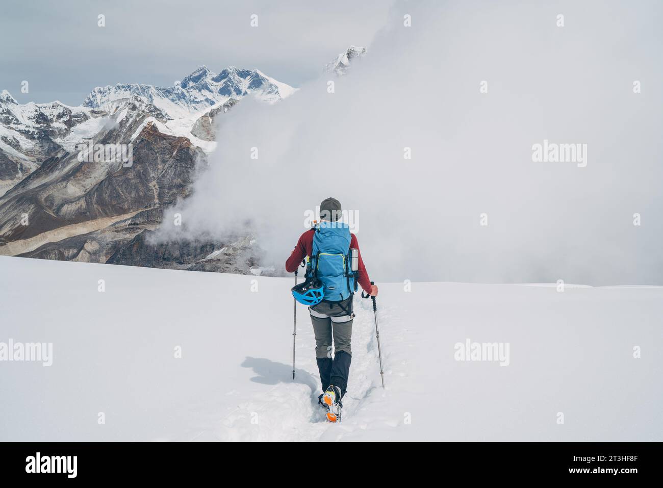 Grimpeur avec sac à dos et bâtons de trekking descendant les hautes pentes du pic Mera à cca 6000m profitant du légendaire mont Everest, Nuptse, Lhotse avec South FAC Banque D'Images
