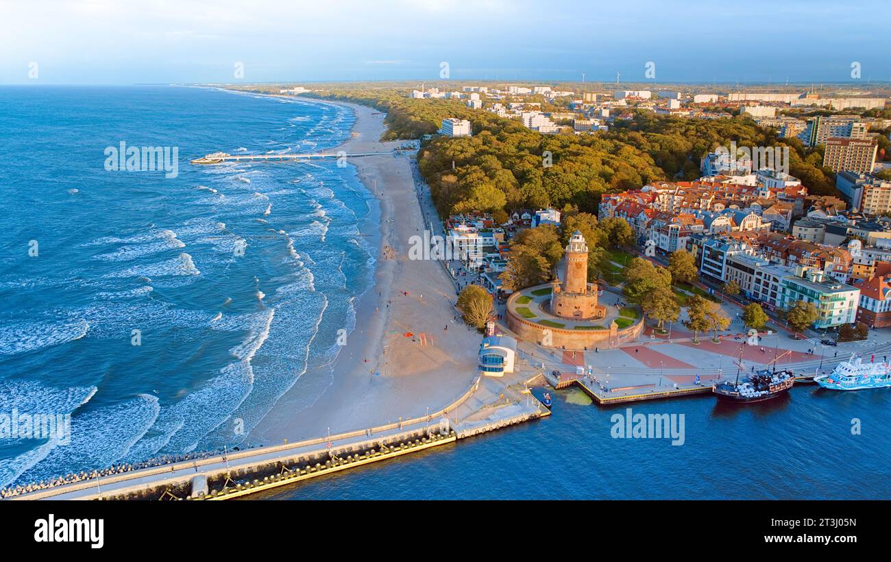 La photo de drone capture le charme maritime de Kołobrzeg, avec le phare emblématique, la mer ceruléenne, les vagues turbulentes, une jetée lointaine. Banque D'Images