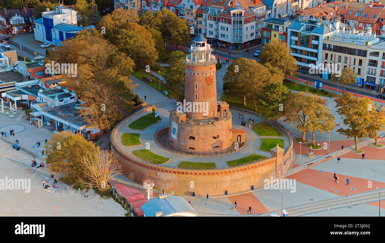 La photo de drone capture le charme maritime de Kołobrzeg, avec le phare emblématique, la mer ceruléenne, les vagues turbulentes, une jetée lointaine. Banque D'Images