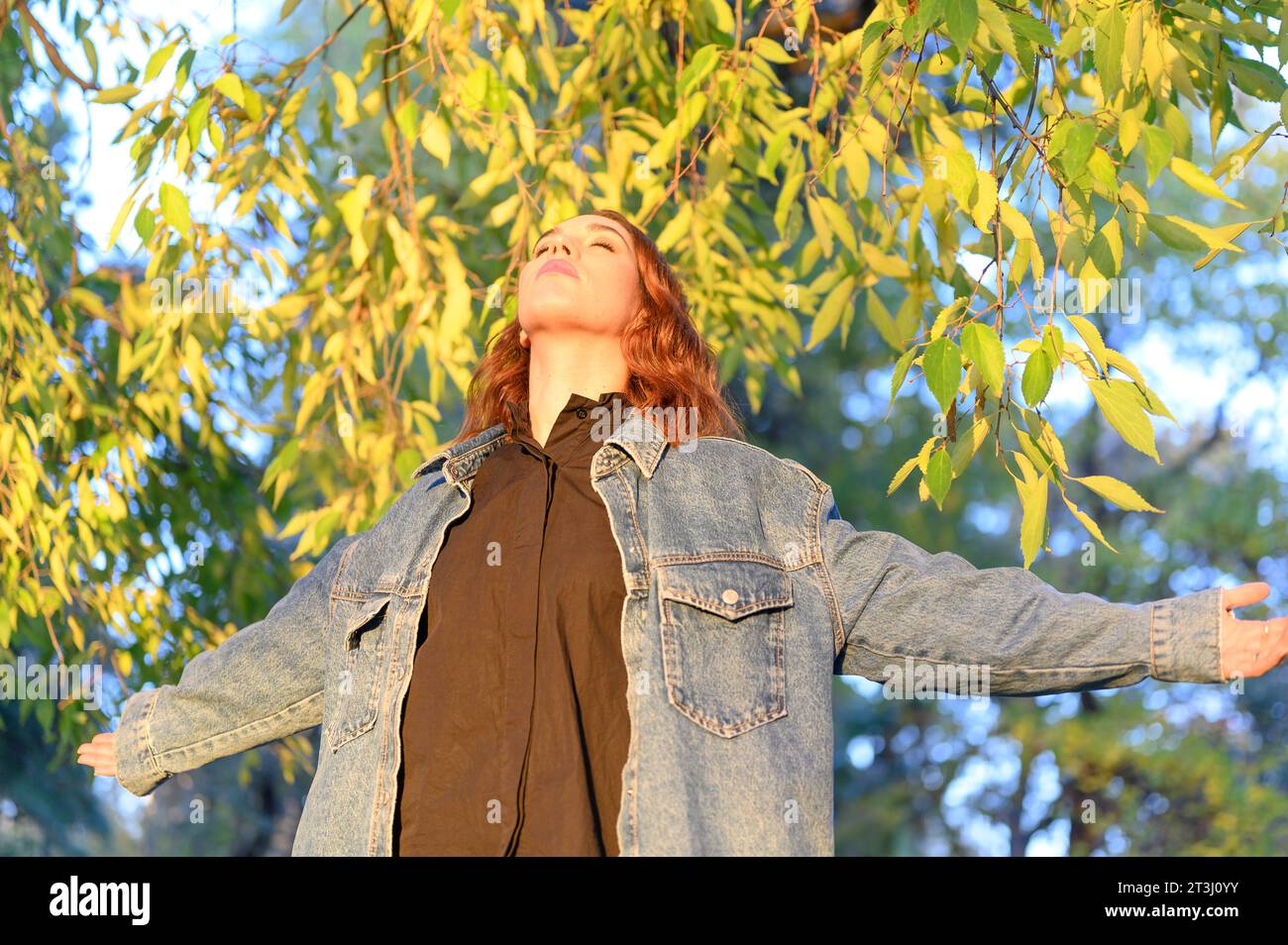 femme aux yeux fermés au coucher du soleil dans le parc Banque D'Images