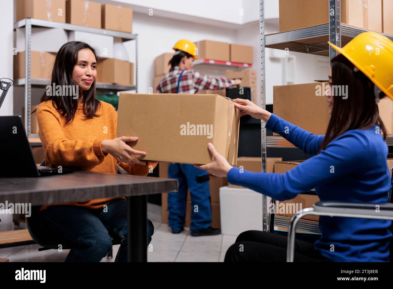 Employé d'entrepôt asiatique handicapé donnant le paquet à un collègue. Responsable logistique de magasin et préparateur de produits inspectant la qualité de la commande et préparant l'envoi dans la salle de stockage Banque D'Images