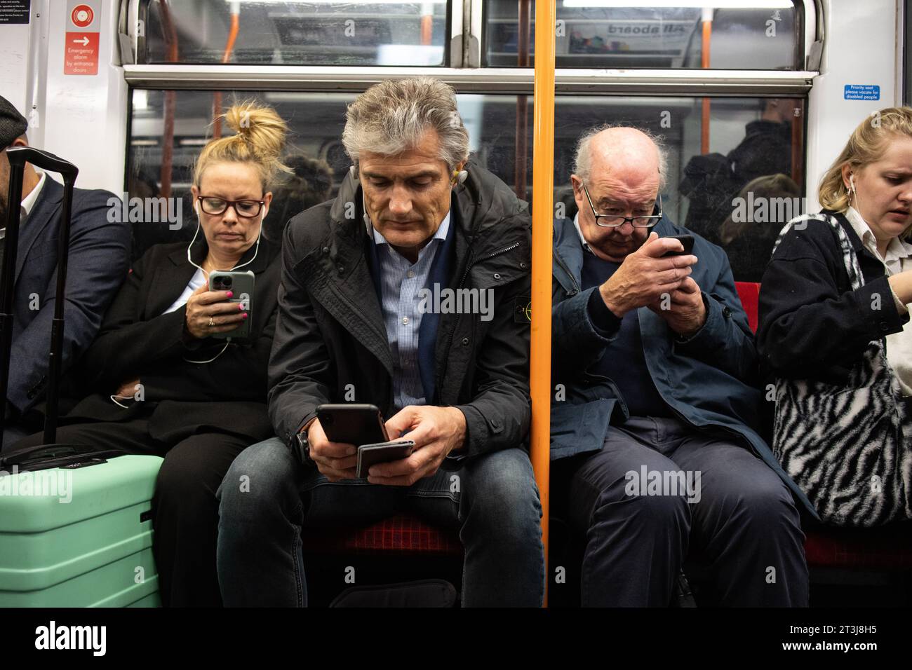 Les navetteurs du South Western Rail se sont entassés sur des sièges surfant sur leur smartphone pendant les heures de pointe dans un train sortant de la gare principale de Londres Waterloo. Banque D'Images