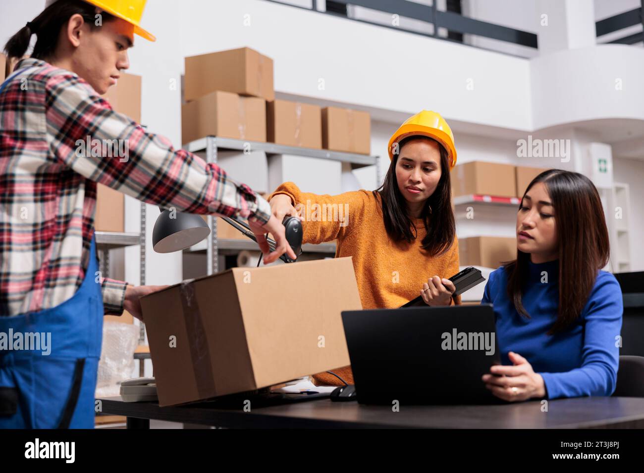 Manutentionnaire de colis et opérateurs de livraison asiatiques préparant le colis pour l'expédition. Employés de l'entrepôt de bureau de poste collègues utilisant le lecteur de code-barres et vérifiant la commande du client sur l'ordinateur portable Banque D'Images