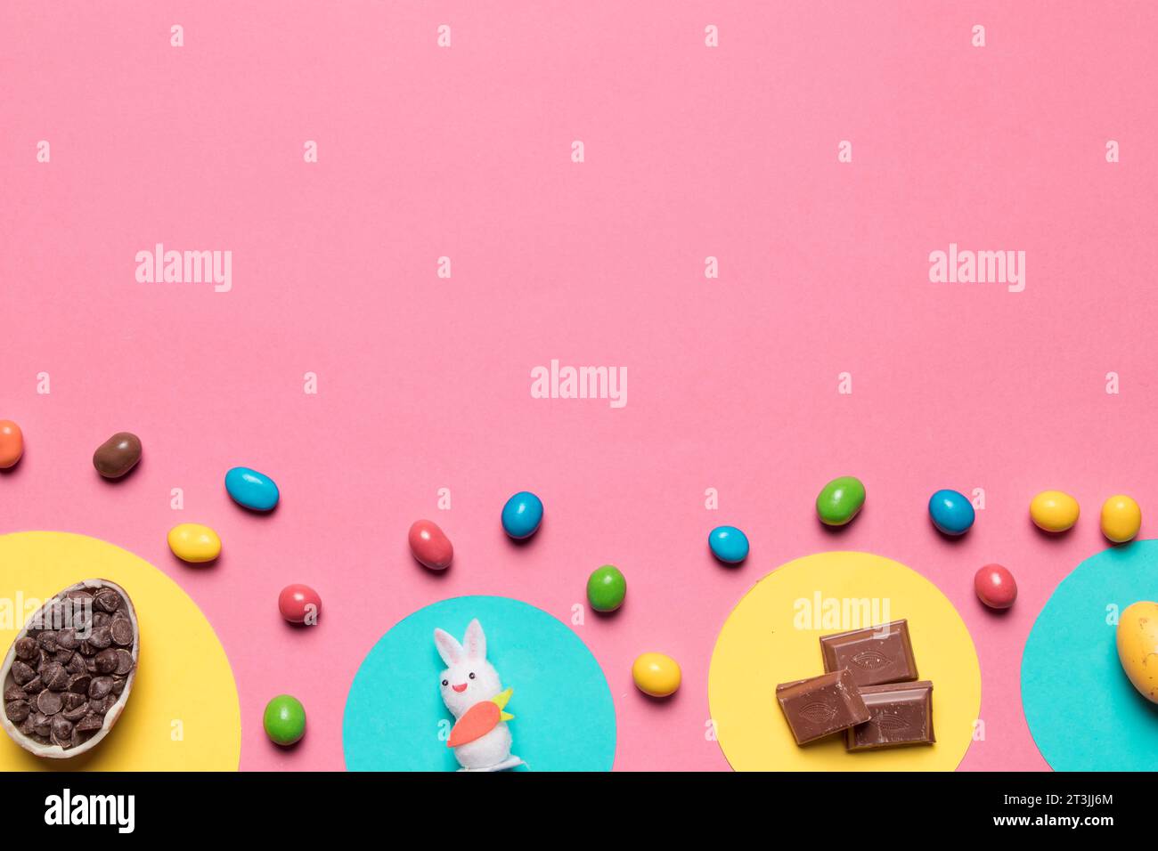 Choco Chips lapin statue morceaux de chocolat bonbons colorés fond rose avec texte espace Banque D'Images