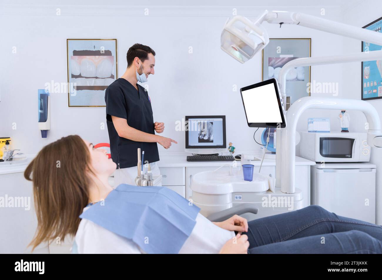 Dentiste masculin expliquant les dents écran de rayons X patient femelle couché chaise de dentiste Banque D'Images