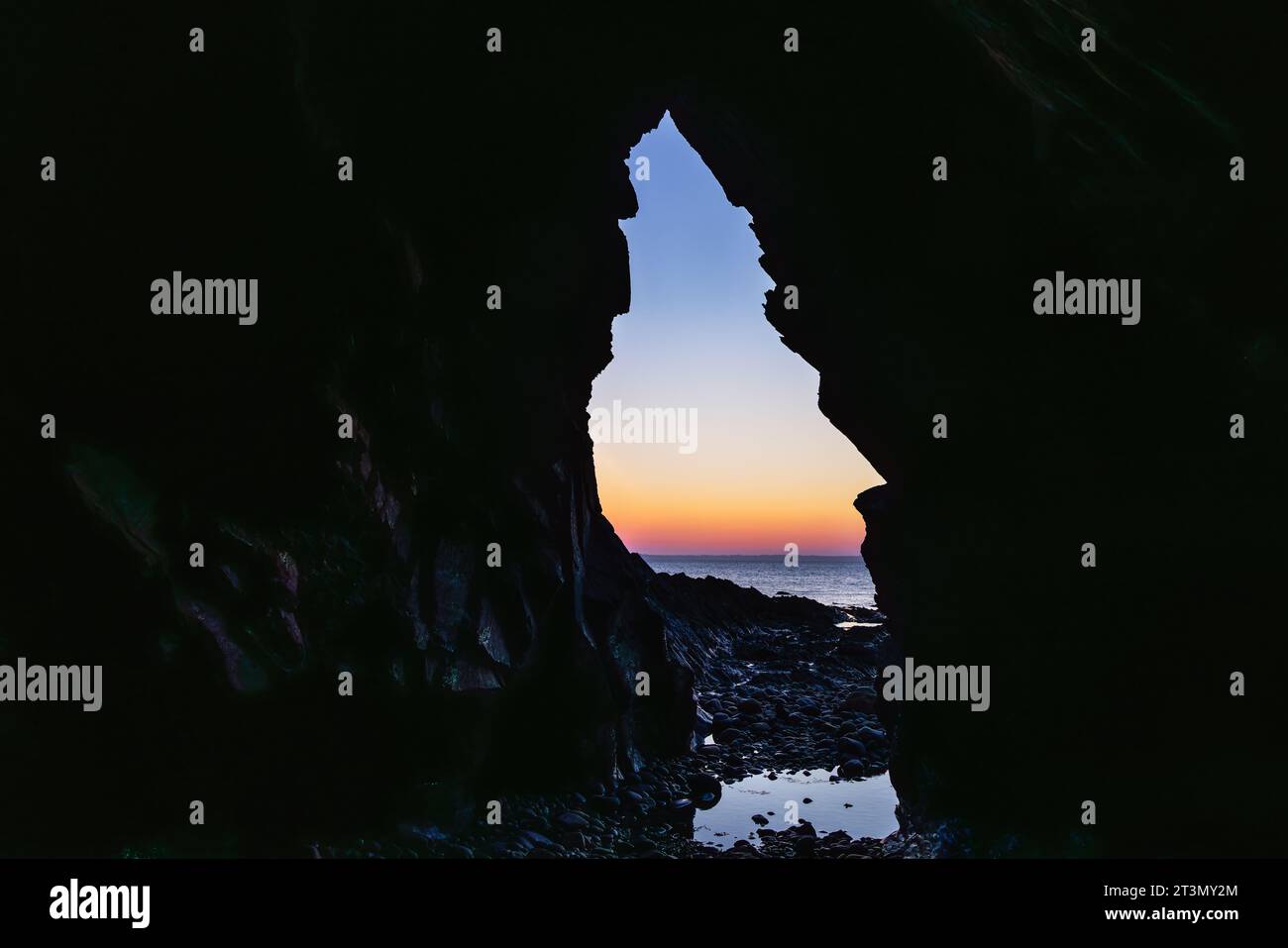 Vue hors d'une grotte à la mer avec coucher de soleil, sur la péninsule de Crozon, Bretagne France Banque D'Images