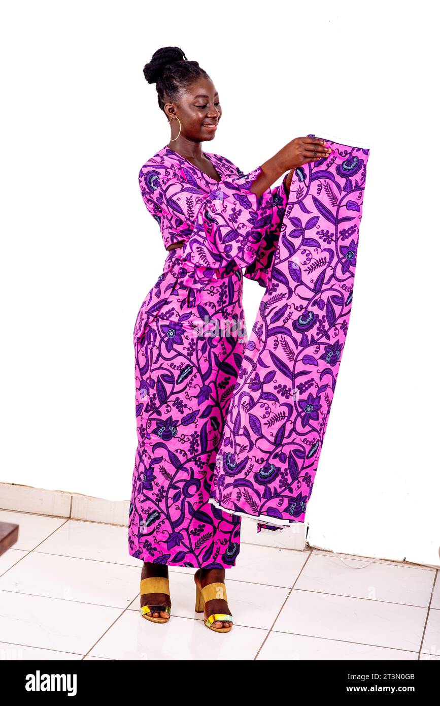 Portrait d'une belle jeune femme d'affaires africaine tenant un longe traditionnel tout en souriant. Banque D'Images