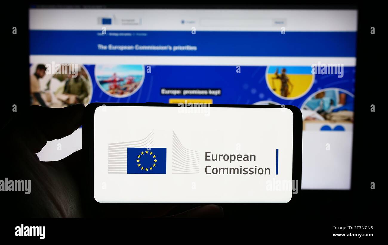 Personne détenant un smartphone avec le logo de l'institution de l'UE Commission européenne (ce) devant le site web. Concentrez-vous sur l'affichage du téléphone. Banque D'Images