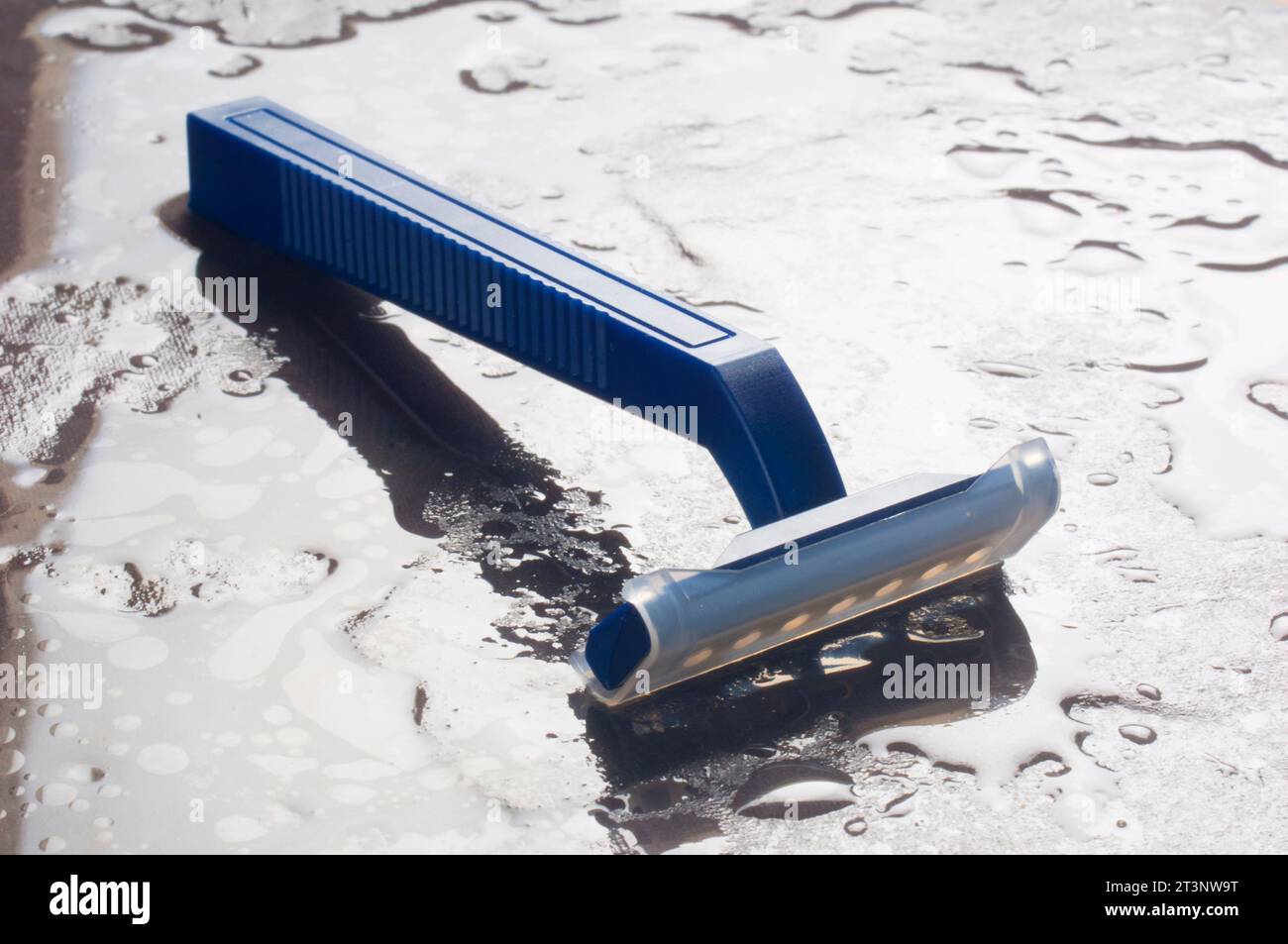 Photo de studio d'un rasoir jetable en plastique sur un fond d'ardoise humide - John Gollop Banque D'Images